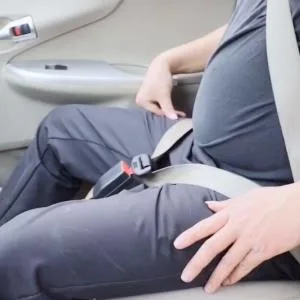 How should pregnant women wear a seat belt?